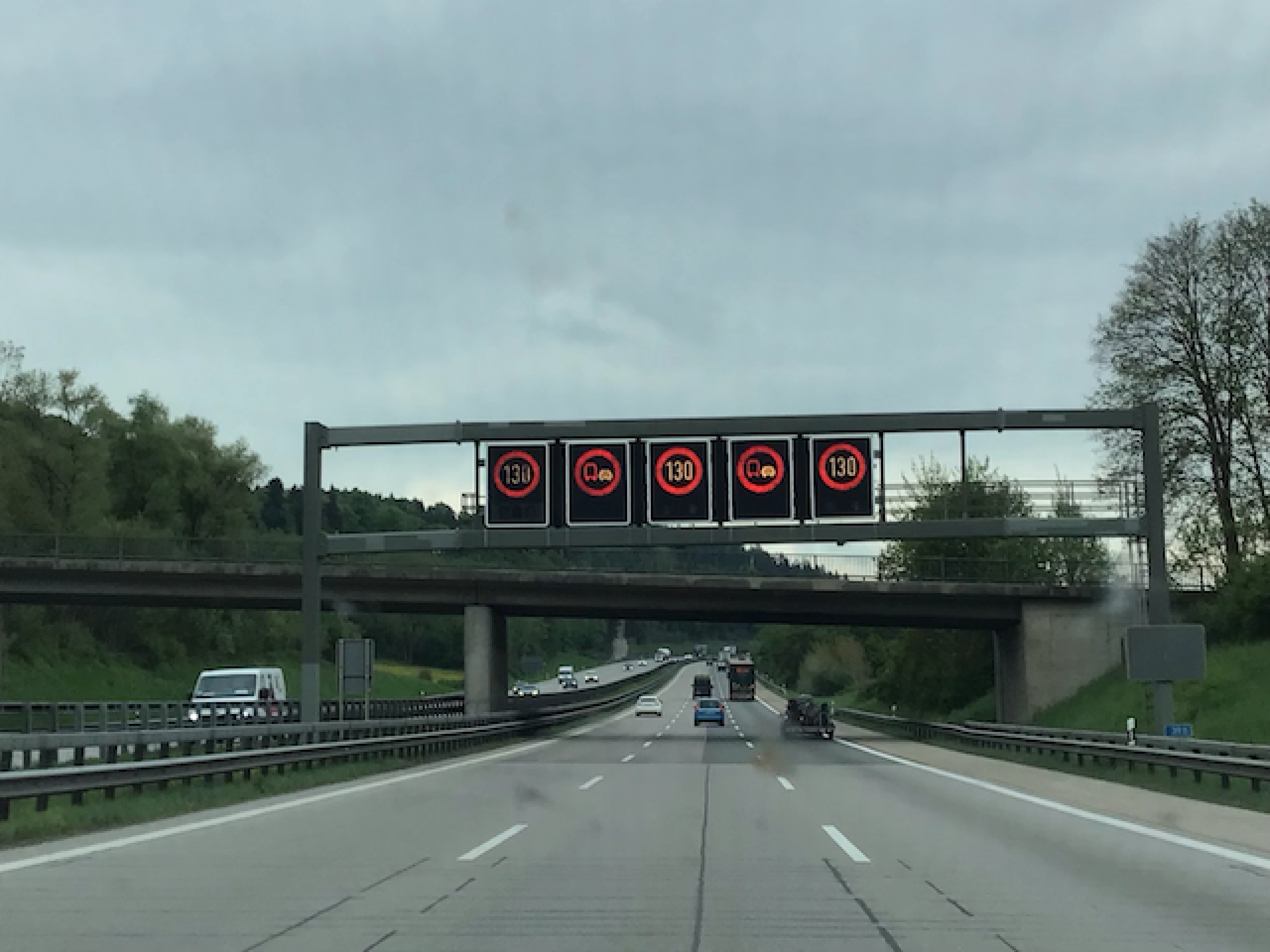 Dynamic road signs on the Autobahn display a temporary speed limit of 130 km/h and a no-passing restriction for trucks. These variable signs adjust based on traffic, weather, or construction conditions to enhance safety on unrestricted stretches.